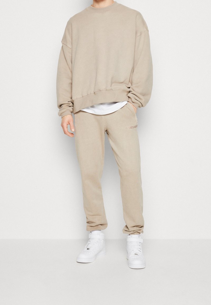 Beige oversized sweatshirt och matchande joggers i mjukt tyg med resåren vid anklarna. Vita sneakers fulländar den avslappnade outfiten.