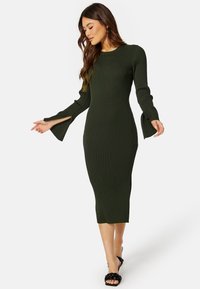 Abito midi a maglia rigata di colore verde scuro, con maniche lunghe a campana e polsini con spacco. Presenta un collo rotondo e una silhouette aderente.
