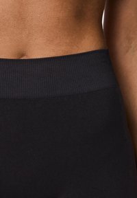Leggings neri elasticizzati a vita alta, texture liscia, copertura totale, cuciture minime, adatti per attività sportive o uso casual.