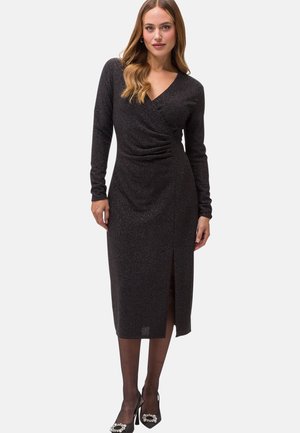 Schwarzes, langärmliges Kleid mit Wickeldesign, aus strukturiertem Stoff, seitlichem Schlitz und mittellanger Länge bis zur Wade. Mit subtiler Glanzakzenten.