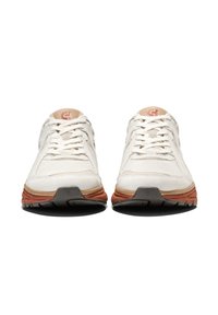 Zapatillas deportivas de color claro con parte superior texturizada, fabricadas en tejido sintético y suelas de goma. Incluyen detalles en naranja contrastante y logotipo.