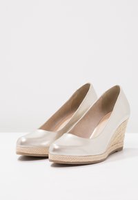 Bottines wedge en beige métallisé avec un bout arrondi et un talon en jute tressé. Texture lisse et design simple, idéales pour une tenue décontractée ou semi-formelle.
