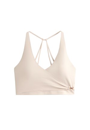Vaalea beige bralette, jossa on syvä V-pääntie, säädettävät ristikkäiset takanauhat ja koristeellinen sivusolmu, jossa on kultainen yksityiskohta.