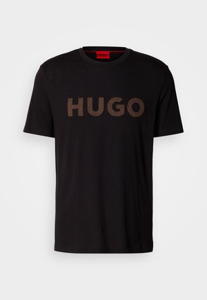 Black cotton t-shirt featuring a large, textured bronze "HUGO" logo on the front. It has a round neckline and short sleeves.
