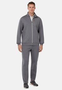 Veste de sport grise à fermeture éclair avec col montant et pantalon de jogging assorti. Tissu lisse avec poches latérales et détails de fermeture éclair contrastants.