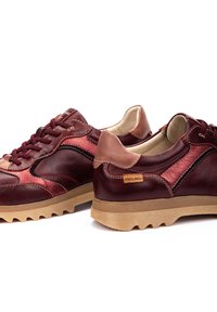 Baskets en cuir rouge et bordeaux avec une finition texturée, accents contrastants en tan et semelle robuste. Présente un design traditionnel à lacets.