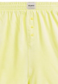 Jasnożółte bokserki z materiału z elastycznym pasem, z metką na górze i czterema guzikami z przodu.