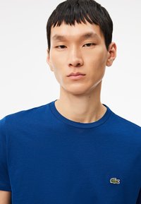 T-shirt di cotone blu royal con scollo rotondo e maniche corte, caratterizzata da un piccolo logo di coccodrillo ricamato sul petto.