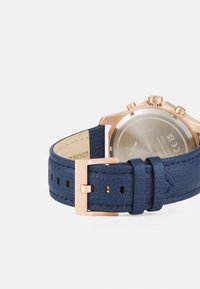 Bracciale in pelle blu navy con finitura testurizzata, dotato di una fibbia e cassa in metallo oro rosa, e un retro della cassa in argento liscio.