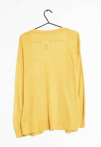 Långärmad, lös passform topp i klar gul färg, tillverkad av lättviktsmaterial. Har en rundad halsringning och fåll med sidoklyftor.