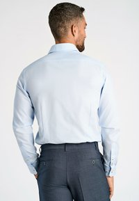 Lichtblauw overhemd met lange mouwen, voorzien van een gestructureerd patroon, met knoopmanchetten en een klassieke kraag, gecombineerd met donkergrijze op maat gemaakte broek.