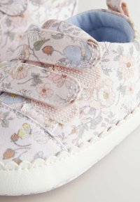 Scarpine per bambini con motivo floreale in morbido tessuto rosa e bianco, dotate di cinturini in Velcro e un interno azzurro chiaro, con una suola testurizzata.