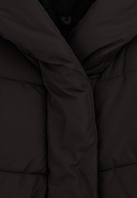 Melna pūkaina jakas ar augstu apkakli, quilted dizainu un mīkstu tekstūru ar spīdīgu ārējo audumu. Nav redzama aparatūra vai raksti.