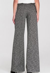 Spodnie o szerokich nogawkach w czarno-białym wzorze pepitki; teksturowana tkanina z wysokim paskiem; widoczne kieszenie; staranne wykończenie na dole.