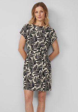 Robe noire et beige à motif, avec des manches courtes, un col rond, et une taille cintrée, présentant un motif de feuilles sur un tissu texturé.