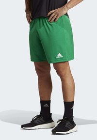 Groene sportshorts gemaakt van synthetisch materiaal, met een elastische tailleband en een wit Adidas-logo op de rechter voorkant.