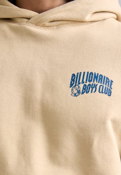 Bežinis sportinis džemperis su mėlynu "BILLIONAIRE BOYS CLUB" grafiniu logotipu ir astronauto simboliu, pagamintas iš švelnaus medvilnės audinio su tekstūruotu paviršiumi.