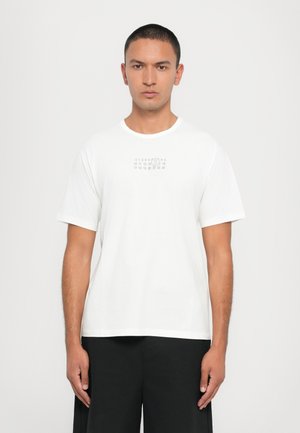T-shirt en coton blanc avec un petit graphique imprimé de chiffres sur la poitrine. Manches courtes et encolure ronde avec une base droite.