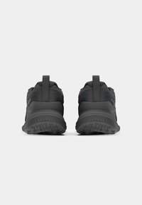 Black athletic shoes with textured mesh upper, padded collar, and rubber outsole featuring a grippy tread pattern. Two loops for easy wear.