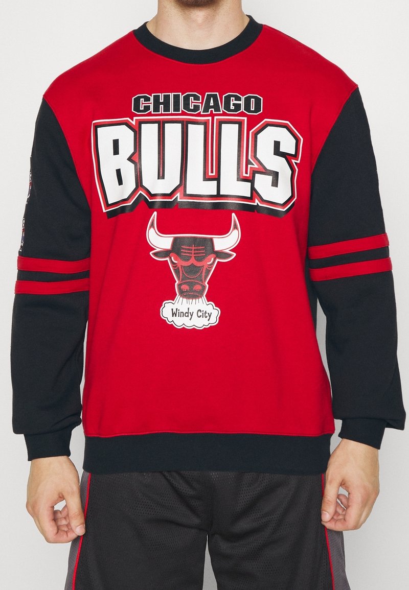 Sudadera roja y negra con el logo de "Chicago Bulls", gráfico de un toro y el texto "Windy City". Mangas largas con dos rayas rojas en cada una.