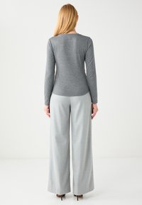 Gray long-sleeve top with a fitted silhouette, paired with wide-leg gray trousers. Smooth texture, simple design, no visible patterns.