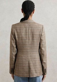 Hnedý károvaný blazer s prispôsobeným strihom, jedným zadným rozventom, klopami s výrezom a manžetami na tri gombíky. Materiál má textúrovanú väzbu.