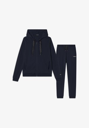Tuta in blu navy composto da una felpa con cappuccio e zip, dotata di cordini, e pantaloni coordinati, entrambi realizzati in materiale morbido con dettagli del logo.