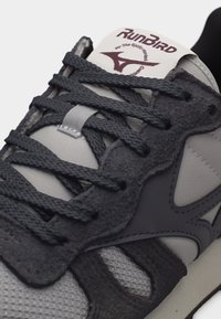 Κοντινό πλάνο γκρι και μαύρου αθλητικού παπουτσιού RunBird με υφασμάτινα κορδόνια, δίχτυστο μπροστινό μέρος και λογότυπο στη γλώσσα.