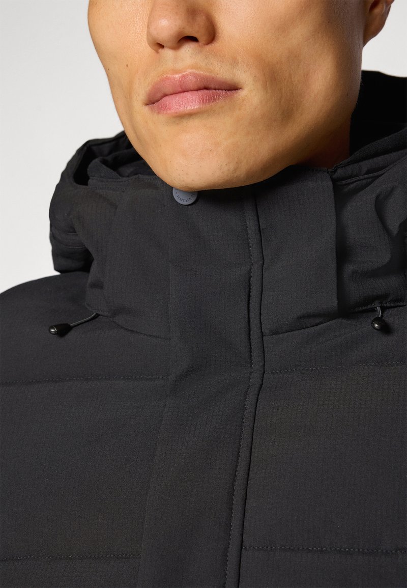 Schwarze isolierte Jacke mit hohem Kragen, aus strukturierter Stoff hergestellt, mit Knopfverschluss und verstellbaren Kordelzügen am Hals.