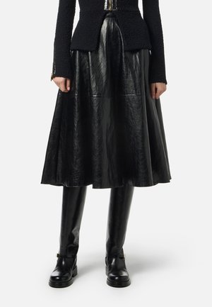Black leather A-line skirt with a shiny texture, paired with fitted black leather knee-high boots featuring minimal hardware.