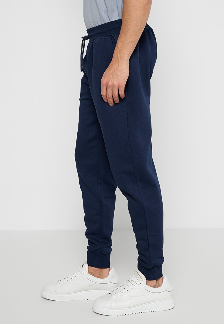 Pantaloni jogger blu navy realizzati in un tessuto morbido, dotati di una vita elastica con coulisse, gambe affusolate e polsini a coste.
