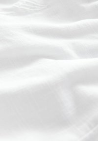 Vitt tyg med en mjuk, slät textur, som visar på lätt skrynklighet och en genomskinlig kvalitet. Ett konsekvent vävmönster är synligt.