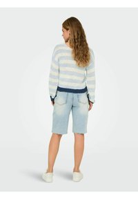  Lichtblauwe gestreepte trui met een marineband aan de onderrand, gecombineerd met vervaagde denim shorts met ruwe randen, gedragen met witte sneakers.