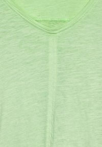 Lys grøn V-hals t-shirt lavet af blødt, struktureret stof med et subtilt heather-mønster og forstærket syning langs halsudskæringen.