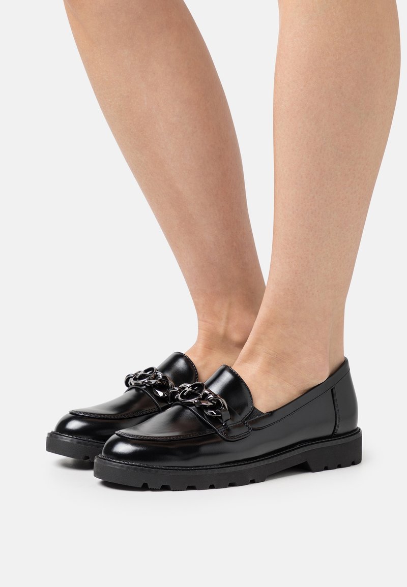 Mocassins en cuir noir avec un détail de chaîne épaisse sur le devant, un bout arrondi et une semelle en caoutchouc noir texturée.