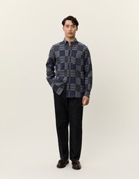 Πουκάμισο καρό με κουμπιά σε ναυτικό μπλε με ανοιχτό γκρι λεπτομέρειες, με άνετη γραμμή και τσέπη στο στήθος. Συνδυάζεται με μαύρο παντελόνι και καφέ παπούτσια.