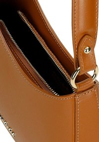 Sac à main en simili cuir marron avec une forme structurée, présentant une poche zippée, des finitions en métal doré et des détails de couture contrastés.