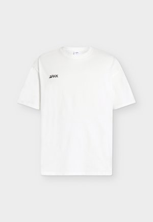 T-shirt bianca a maniche corte con collo rotondo e piccolo logo nero "ARKK" sul petto sinistro, mostrata su uno sfondo chiaro uniforme.