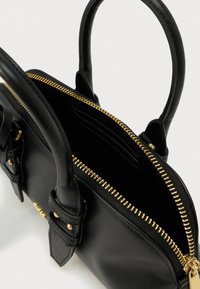 Mala preta de couro com fecho dourado, duas pegas e compartimentos interiores para cartões. Apresenta uma forma estruturada e detalhes de design minimalistas.