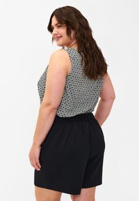 Top senza maniche con un motivo geometrico in bianco e nero, abbinato a pantaloni corti neri con vita elastica. Tessuto morbido e vestibilità rilassata.