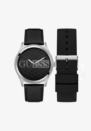 Svart läderrem klocka med ett silvermetallcase, svart texturerad urtavla med "GUESS" och silverfärgade visare. Inkluderar en svart silikonrem.