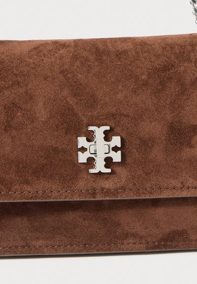 Borsa a spalla in suede marrone con chiusura a emblema argentato. Il design presenta una texture liscia e linee pulite senza motivi visibili.