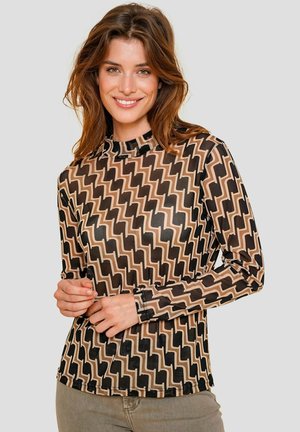 Langsleeve shirt van doorschijnende zwarte stof met een zigzagpatroon in beige. Heeft een hoge kraag en een getailleerd ontwerp.