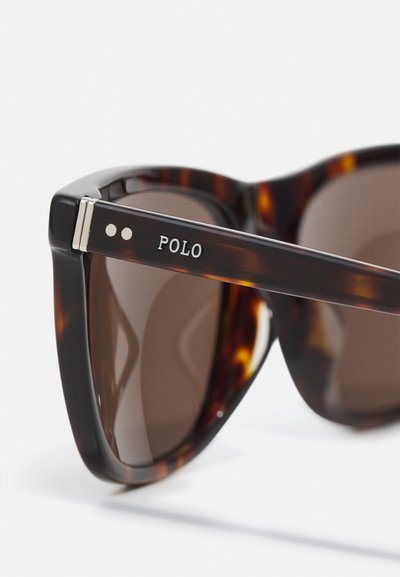 Tortoise-shell sluneční brýle s hnědými skleněnými čočkami, kovovými akcenty a značkou "POLO" na boční straně. Rám s ostrým designem.