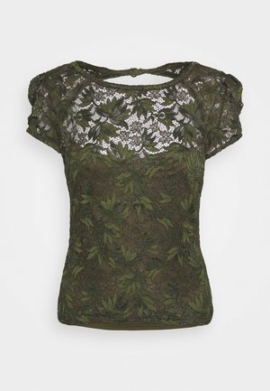 Blouse en dentelle verte foncée à manches courtes avec motif floral et col rond agrémenté d'une petite ouverture en forme de trou de serrure à l'arrière.