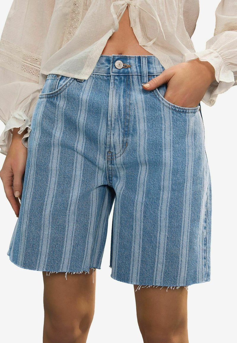 Denim shorts med et lysblåt og hvidt lodret stribet mønster, med en frynset kant og to lommer. Knaplukning i taljen.
