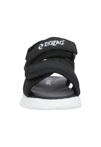 Sort justerbar rem sandal med en tekstureret overdel, hvid gummisål og et mærket logo på remmen. Letvægts og åbent design.