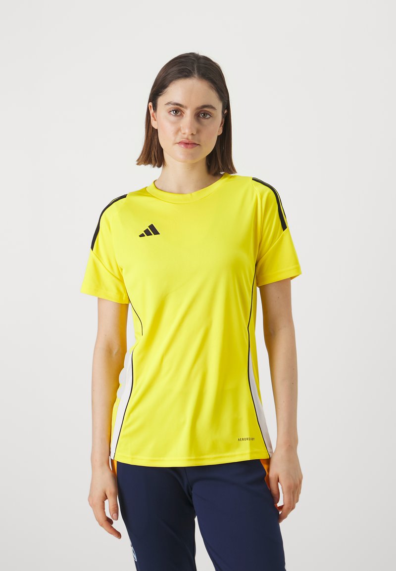 Geltonas sportinis marškinėliai trumpomis rankovėmis, su juodais pečių juostelėmis ir baltais šonais. Pagaminti iš lengvos medžiagos; turi Adidas logotipą.