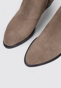 Brown suede ankle boots with a pointed toe design, black rubber sole, and smooth texture. Features a side zipper for easy wear.