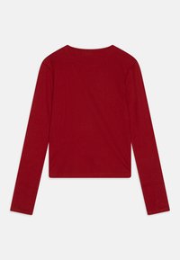 T-shirt rouge à manches longues en tissu lisse, avec un col rond et une coupe décontractée. L'ourlet est droit et se termine au niveau de la taille.